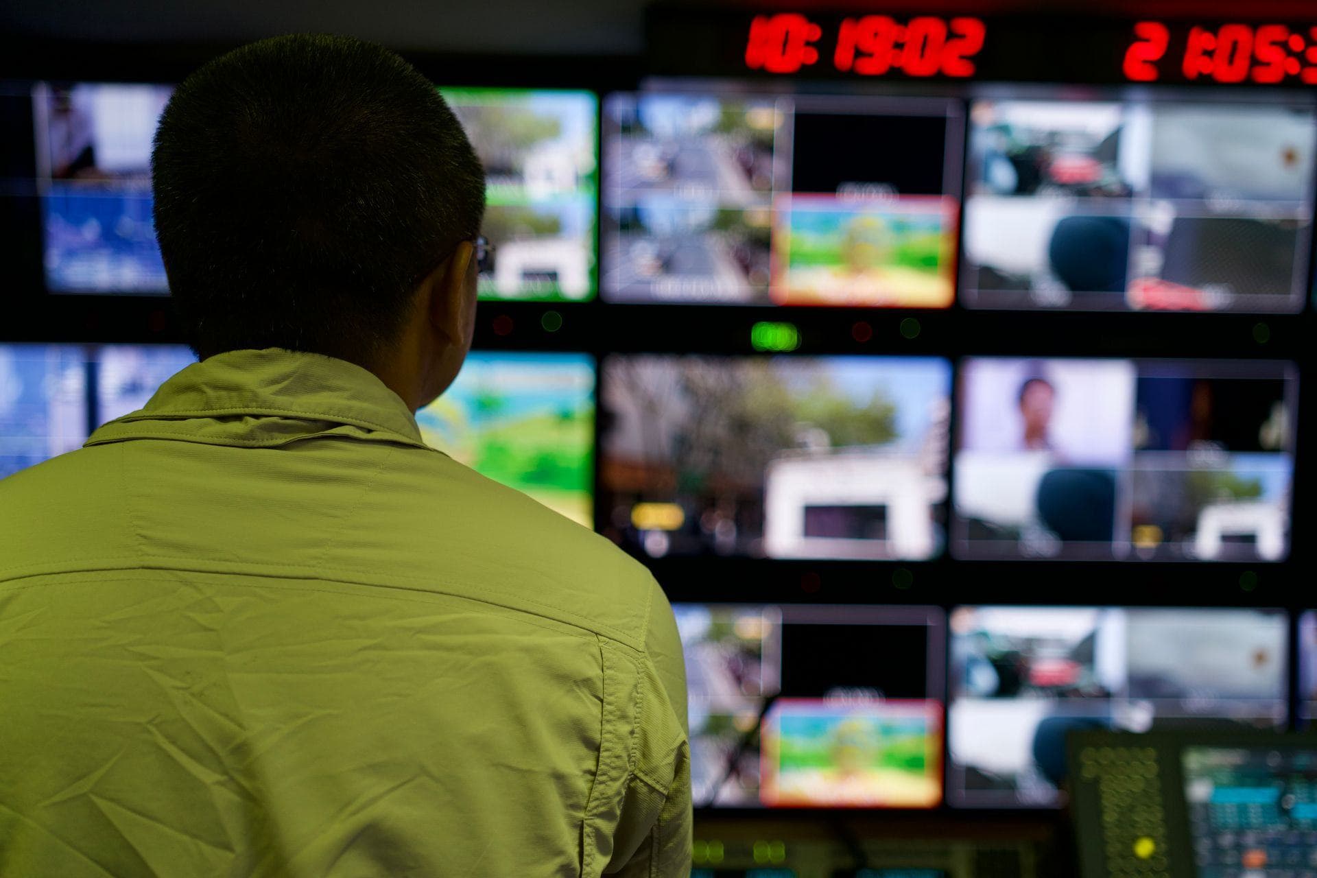 Monitorwand einer Leitstelle, ein Mitarbeiter von hinten vor den Livebildern
